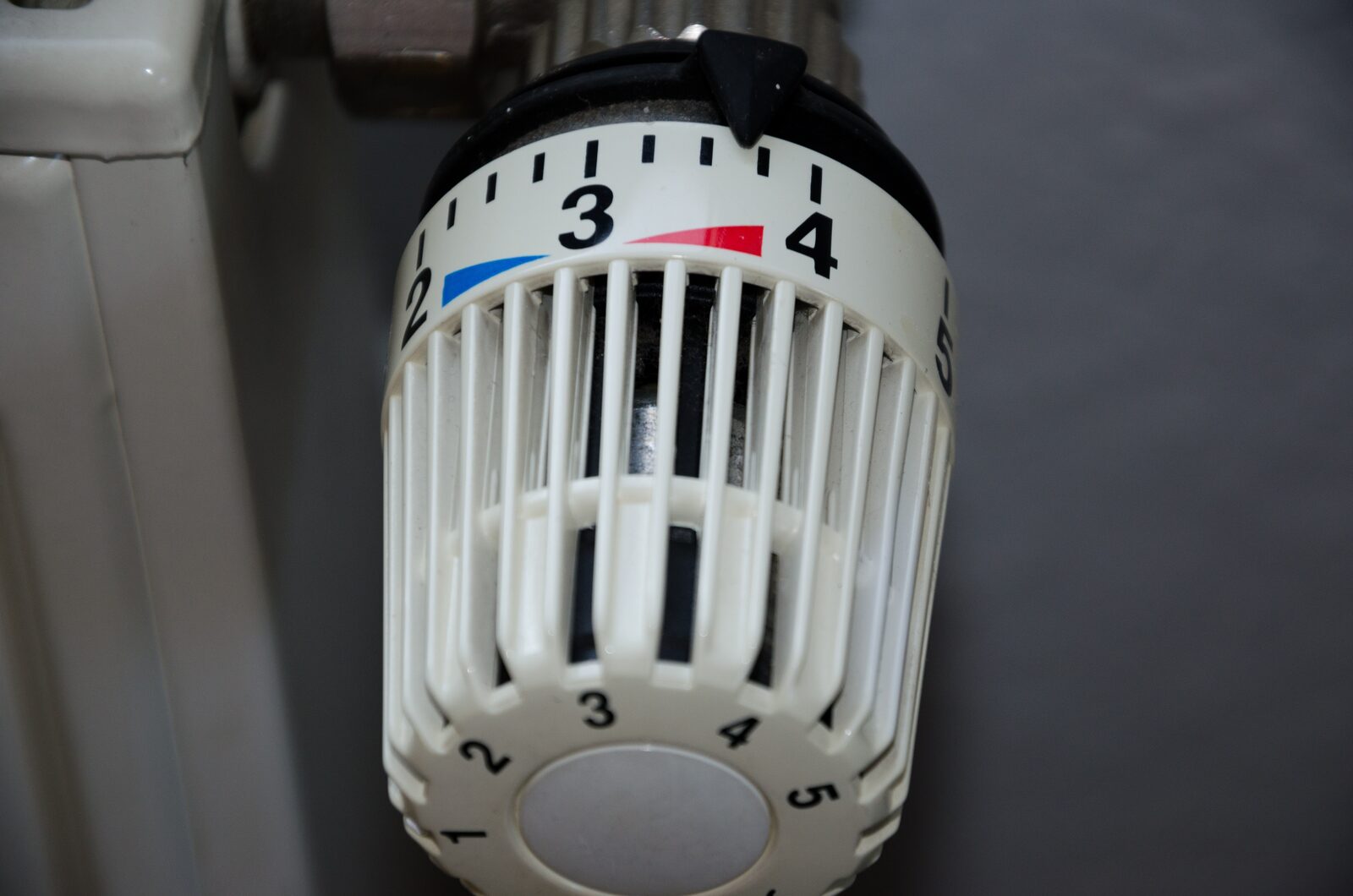 Nahaufnahme eines weißen Heizkörper-Thermostatkopfs, eingestellt zwischen Stufe 3 und 4